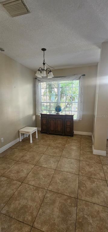 A dining area with tile flooring, a chandelier, a wooden sideboard, and a window with blinds — 8504 SHALLOW CREEK COURT, NEW PORT RICHEY, FL