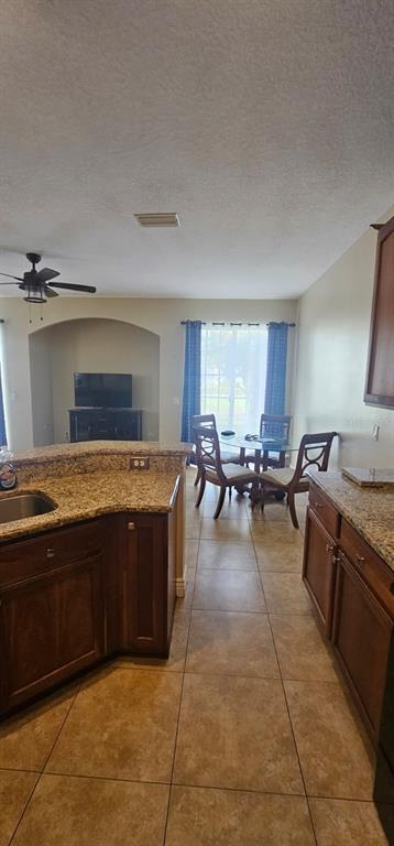 A kitchen with granite countertops and dark wood cabinets overlooks a dining area with windows — 8504 SHALLOW CREEK COURT, NEW PORT RICHEY, FL
