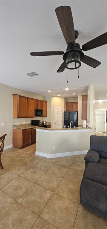 A kitchen with wood cabinets and a breakfast bar opens into a living area — 8504 SHALLOW CREEK COURT, NEW PORT RICHEY, FL