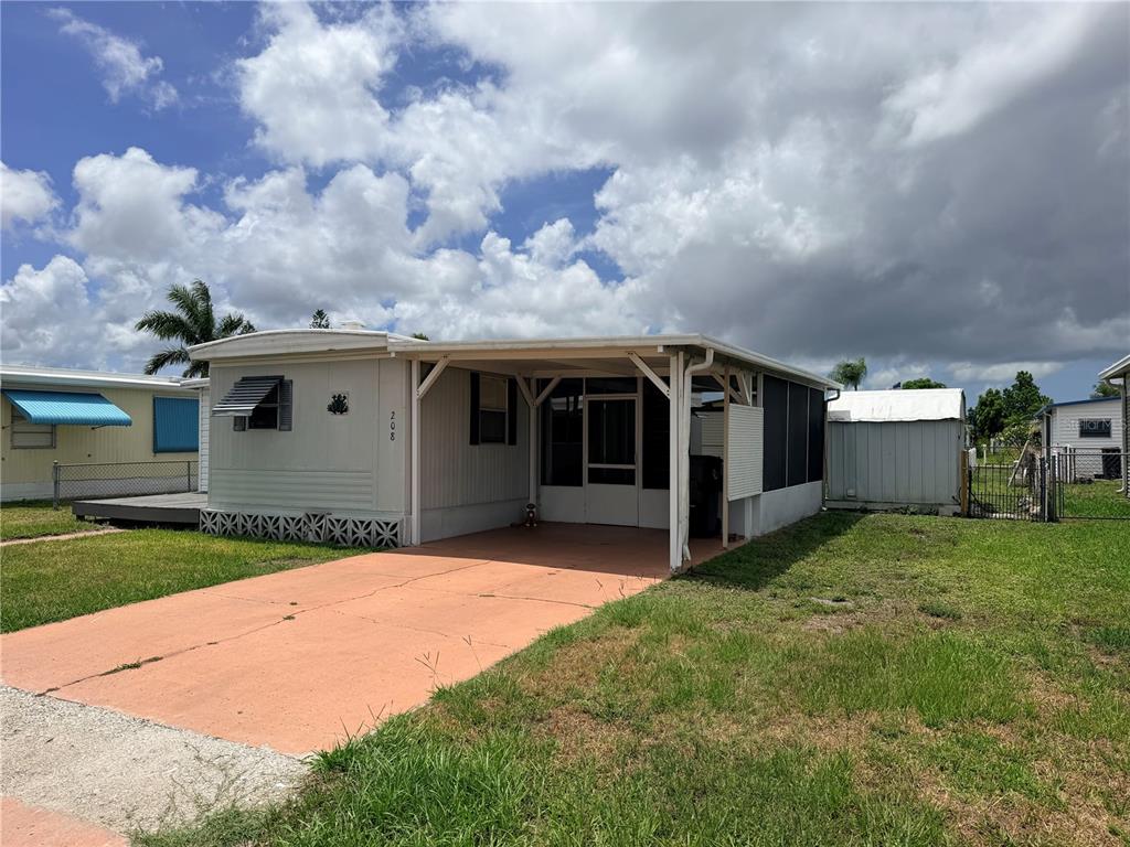 A single-story mobile home with a carport, a screened-in porch, and a concrete driveway — 208 50TH AVENUE DRIVE E, BRADENTON, FL