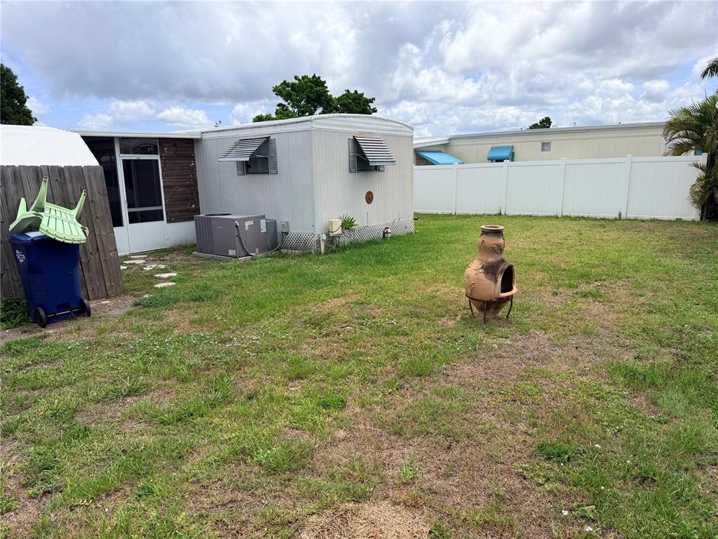 A mobile home exterior features a side yard with a chiminea and a white fence — 208 50TH AVENUE DRIVE E, BRADENTON, FL