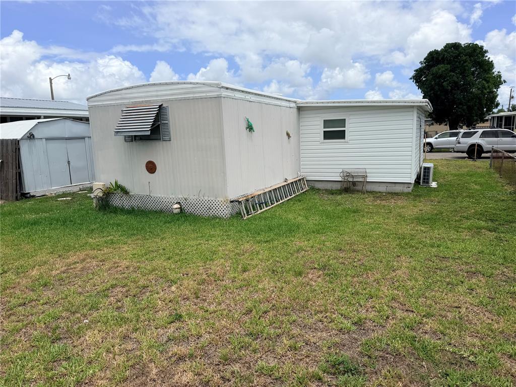 The exterior of a mobile home with a white metal shed and a grassy yard — 208 50TH AVENUE DRIVE E, BRADENTON, FL
