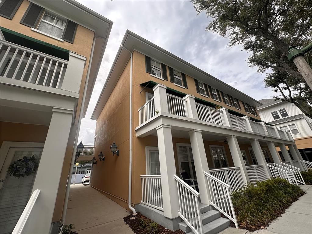 A low-angle exterior view of a multi-story tan building with white porches and balconies — 709 BLOOM STREET UNIT 240, CELEBRATION, FL