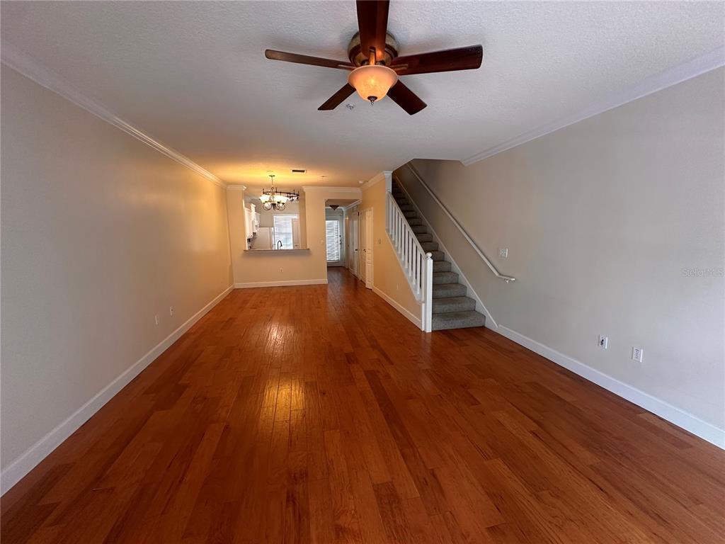 An open living area features hardwood floors, a ceiling fan, and a staircase with carpet — 709 BLOOM STREET UNIT 240, CELEBRATION, FL