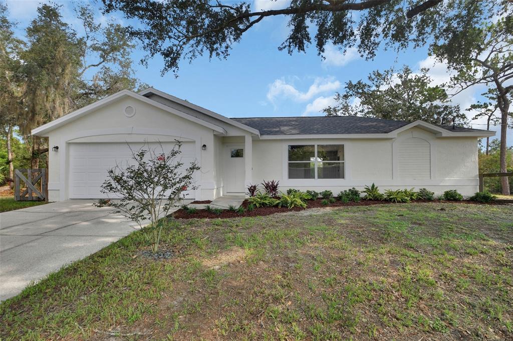 A single-story white house with a two-car garage and a landscaped front yard — 1251 SEMINOLE DRIVE, DE LEON SPRINGS, FL