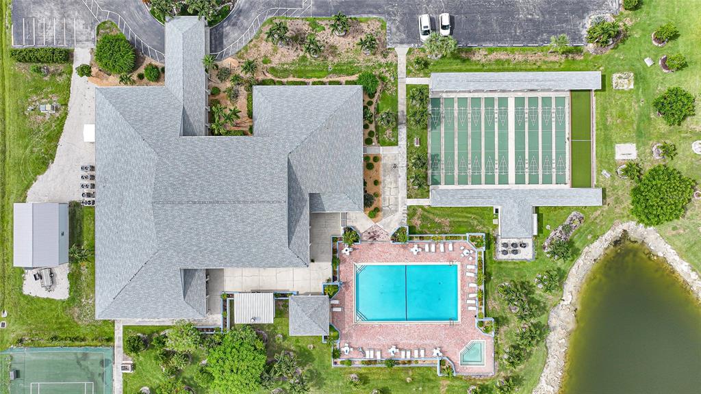 An aerial view shows a building with a pool, shuffleboard courts, and a nearby pond — 16209 ASHEBORO COURT, FORT MYERS, FL