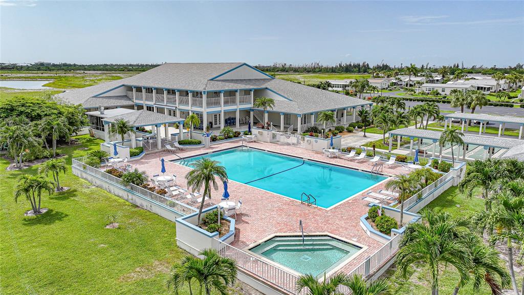 An aerial view of a community swimming pool and hot tub beside a large building — 16209 ASHEBORO COURT, FORT MYERS, FL