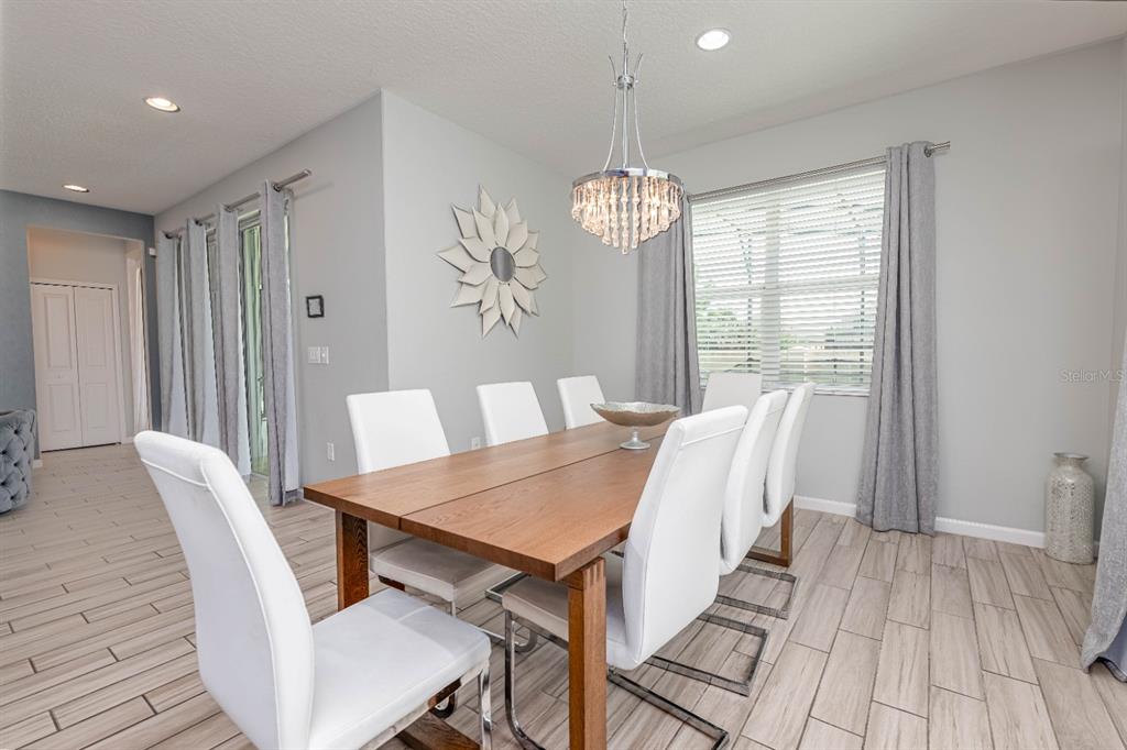A dining room features a wooden table, white chairs, a crystal chandelier, and tile flooring — 2661 CALISTOGA, KISSIMMEE, FL
