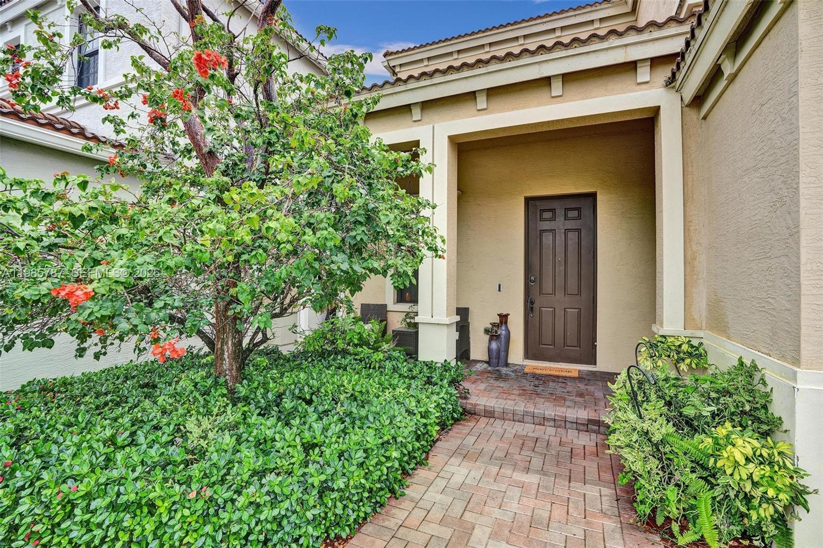 A brick walkway leads to a brown front door under a covered entryway — 760 NE 193rd Ter, Miami FL 33179, MIAMI, FL