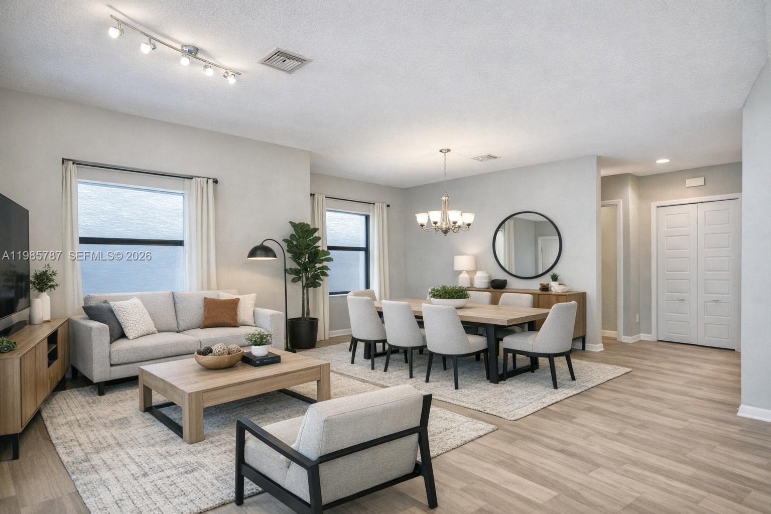 A combined living and dining room features light wood flooring, neutral furniture, and modern lighting — 760 NE 193rd Ter, Miami FL 33179, MIAMI, FL