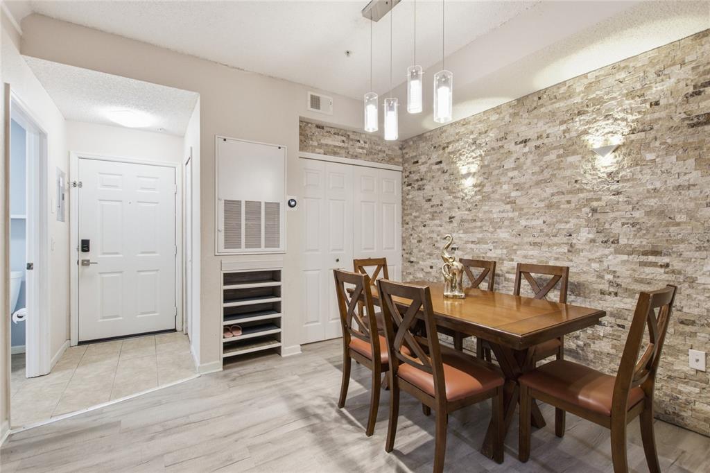 A dining area features a wooden table, four chairs, and a textured stone accent wall — 13037 MULBERRY PARK DRIVE UNIT 518, ORLANDO, FL