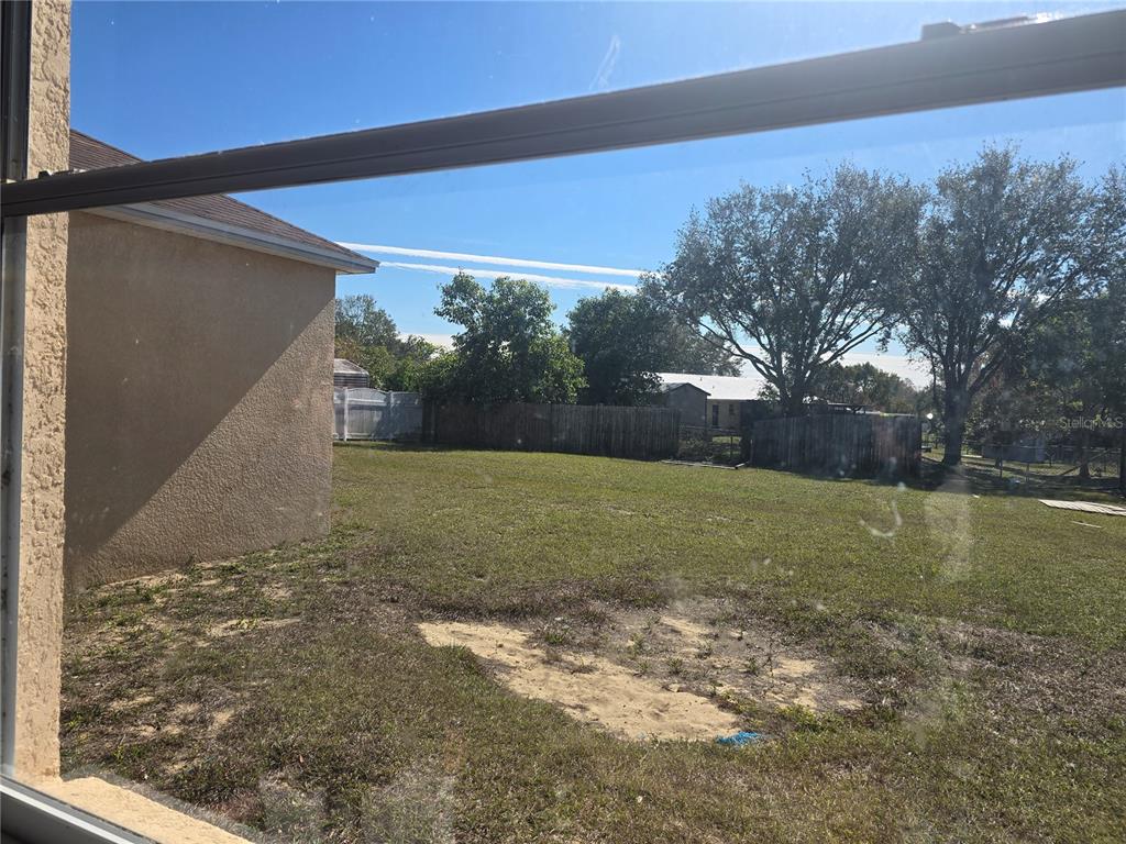 A view from a window looking out onto a grassy backyard with a wooden fence — 4049 BYRDS CROSSING DRIVE, LAKELAND, FL