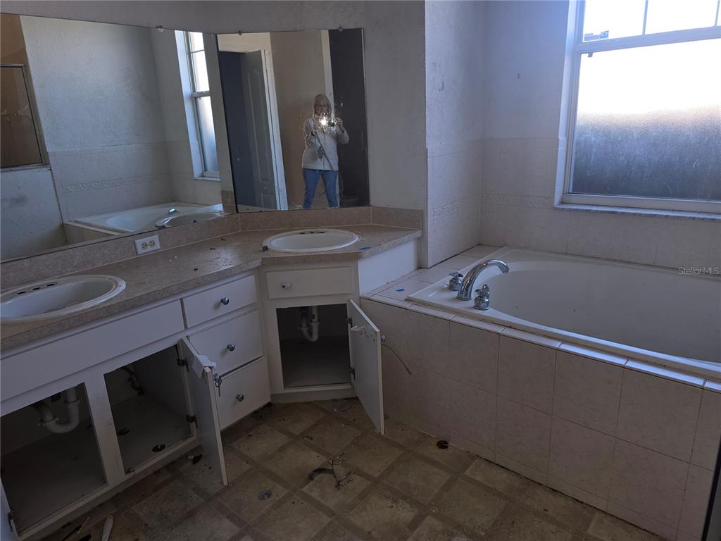 A bathroom features a double vanity with missing cabinet doors, a corner tub, and mirrors — 4049 BYRDS CROSSING DRIVE, LAKELAND, FL