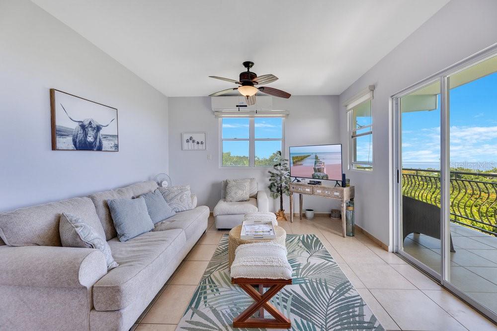 A living room features a sofa, a patterned rug, a ceiling fan, and a balcony view — km 4.1, PR-413 Rincon 006 KM 4.1, PR- 413 RINCON 00677 UNIT A7, RINCON, PR