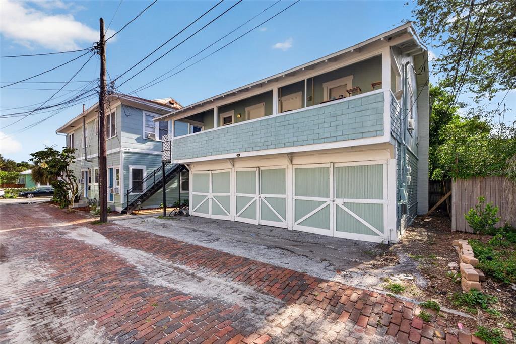 A two-story building with a light green exterior, a balcony, and four ground-level garage doors — 633 7TH AVENUE N, ST PETERSBURG, FL