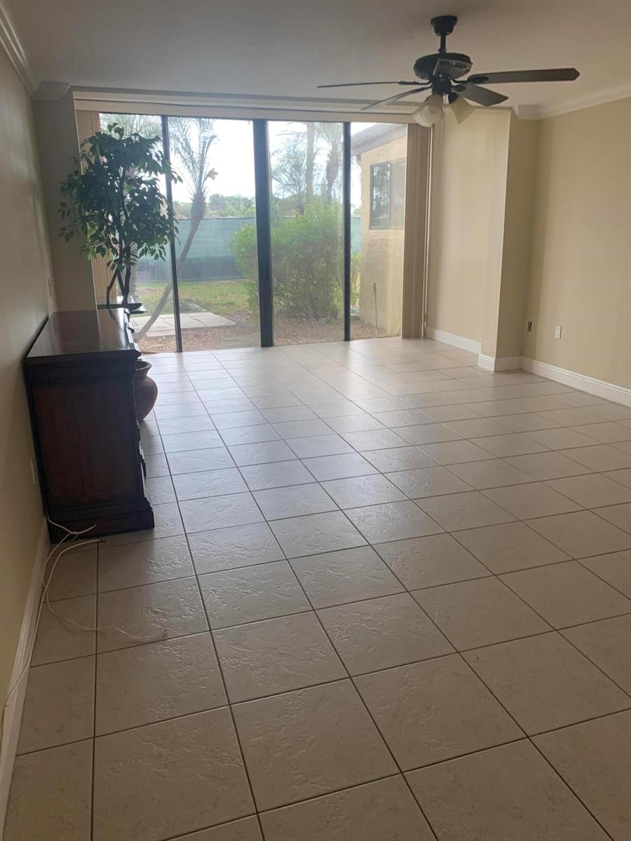 An empty room with beige tile flooring, a ceiling fan, and sliding glass doors — 4236 Deste # 108, Lake Worth FL 33467, LAKE WORTH, FL