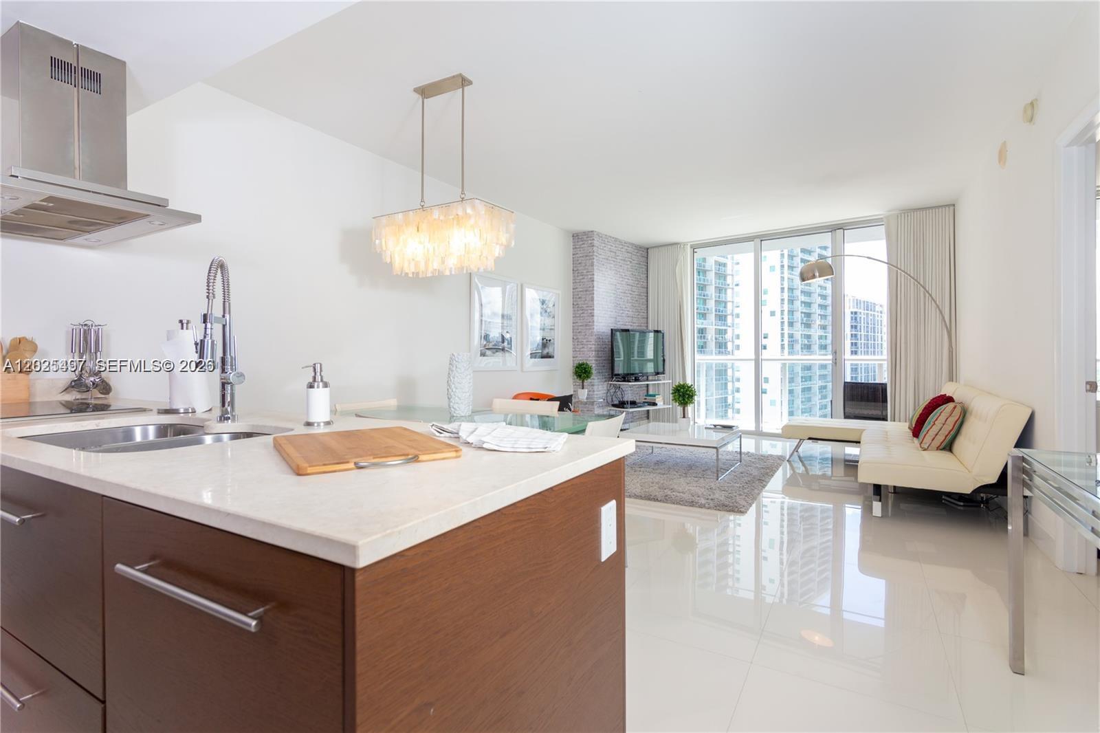 A modern open-concept apartment features a kitchen island, dining area, and living room with balcony — 485 Brickell Ave # 2006, Miami FL 33131, MIAMI, FL