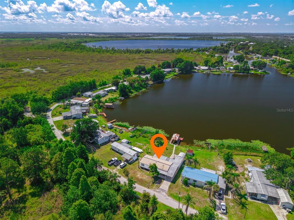 An aerial view shows a house with a metal roof located on a lakefront lot — 2008 LAKE ELLEN DRIVE, HAINES CITY, FL