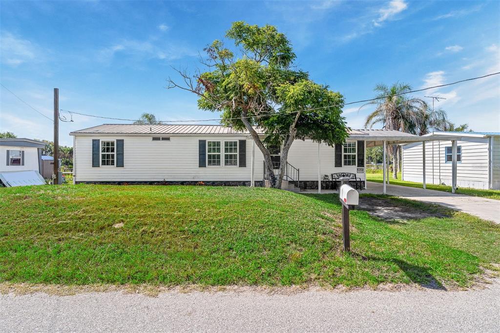 A single-story mobile home with white siding, a metal roof, and a carport — 2008 LAKE ELLEN DRIVE, HAINES CITY, FL
