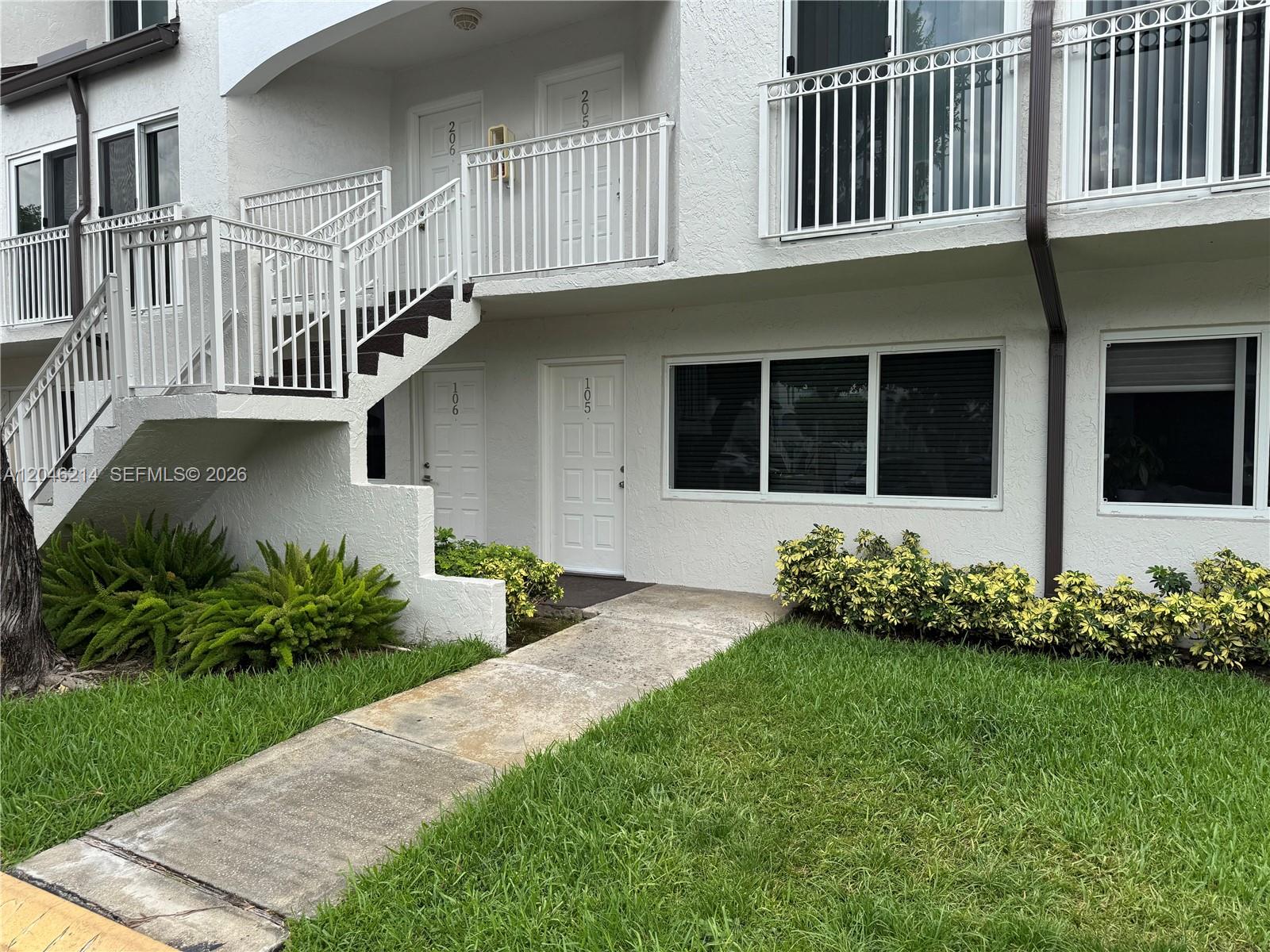 A two-story white apartment building features exterior stairs, balconies, and a concrete walkway — 8695 NW 6th Ln # 105, Miami FL 33126, MIAMI, FL