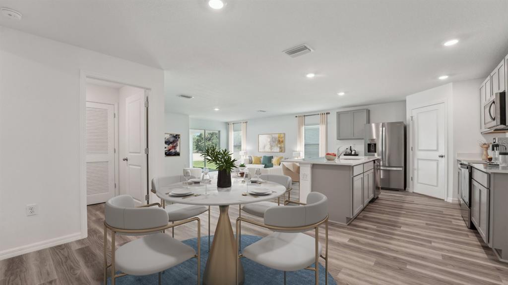 A dining area with a round table sits adjacent to a modern kitchen and living room — 3506 ROSEWOOD RAMBLE COURT, PLANT CITY, FL