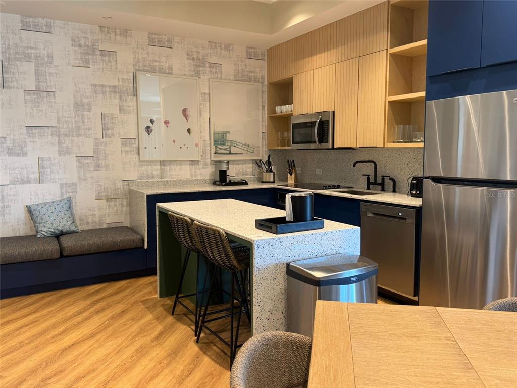 A modern kitchen features a speckled island, blue cabinetry, light wood accents, and a built-in bench — 3151 SUNSET WALK DRIVE UNIT 314, KISSIMMEE, FL