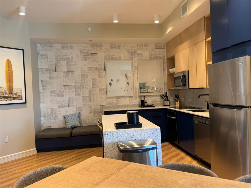 A kitchen with a central island, blue cabinets, stainless steel appliances, and a built-in bench — 3151 SUNSET WALK DRIVE UNIT 314, KISSIMMEE, FL