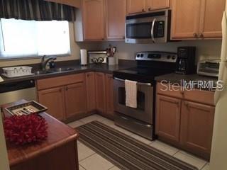 A kitchen with wood cabinets, stainless steel appliances, and a tiled floor — 5271 WILLOW LINKS UNIT 49, SARASOTA, FL