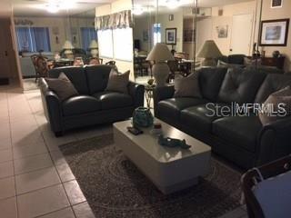 A living room features two dark leather sofas, a coffee table, and mirrored walls — 5271 WILLOW LINKS UNIT 49, SARASOTA, FL