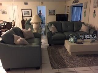 A living room features two teal sofas, a light-colored coffee table, and a patterned area rug — 5271 WILLOW LINKS UNIT 49, SARASOTA, FL