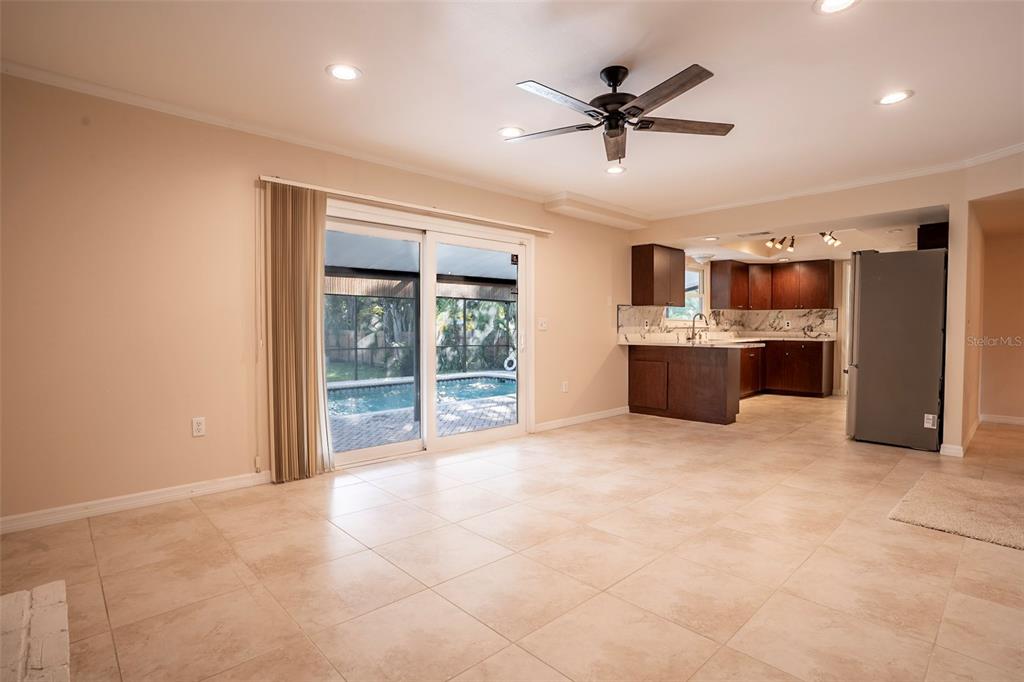 A living room with tile floors and a ceiling fan opens to a pool area — 7324 PHILLIPS STREET, SARASOTA, FL