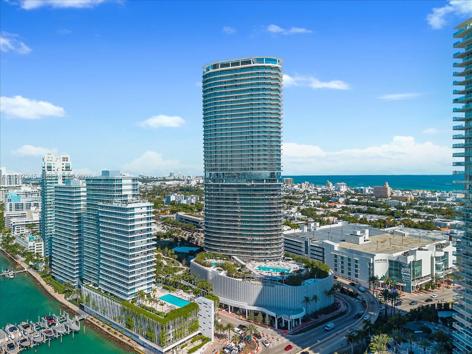 An aerial view shows a tall, cylindrical residential tower surrounded by other buildings and water — 500 Alton Rd # 2402, Miami Beach FL 33139, MIAMI BEACH, FL