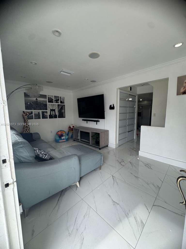 A living room features a grey sectional sofa, a wall-mounted television, and white marble flooring — 8430 NW 8th St # B11, Miami FL 33126, MIAMI, FL