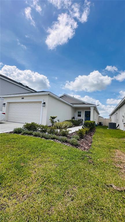 A single-story house with a white exterior, a two-car garage, and a landscaped front yard — 4260 PEBBLES THROW DRIVE, KISSIMMEE, FL
