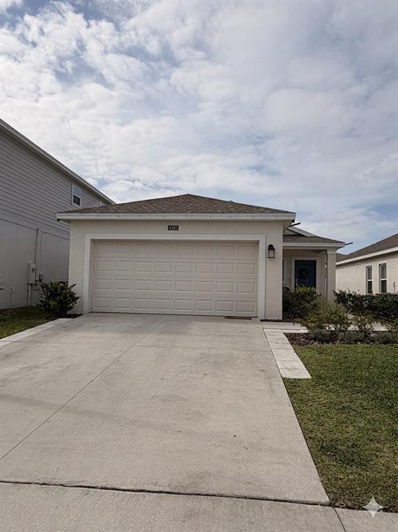 A single-story house features a beige exterior, a two-car garage, and a concrete driveway — 4260 PEBBLES THROW DRIVE, KISSIMMEE, FL