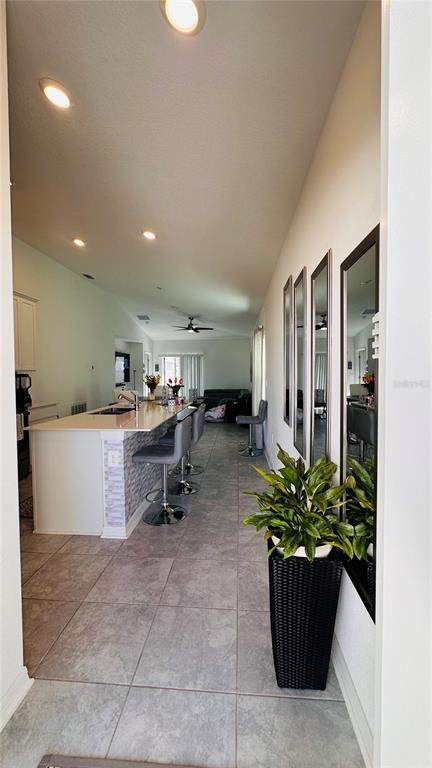 A view from a hallway looking into a kitchen with a breakfast bar and living area — 4260 PEBBLES THROW DRIVE, KISSIMMEE, FL