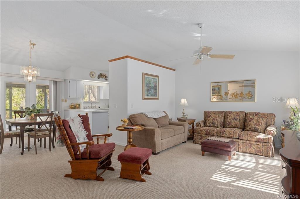 A living room with carpeted floors, a ceiling fan, and an adjacent dining area — 316 PEONY STREET, INVERNESS, FL