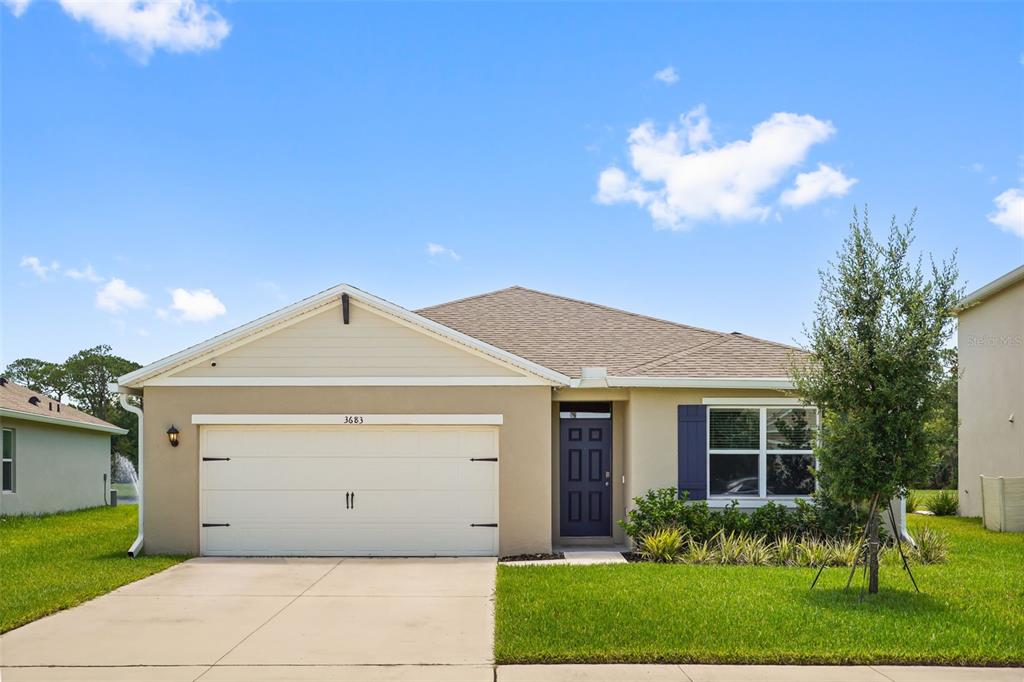 A single-story house with a beige stucco exterior, a two-car garage, and a dark door — 3683 BOTANICAL WAY, SANFORD, FL