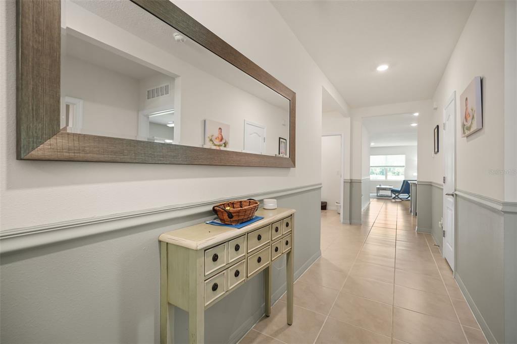 A hallway features a light-colored console table, a large mirror, and tile flooring — 3683 BOTANICAL WAY, SANFORD, FL