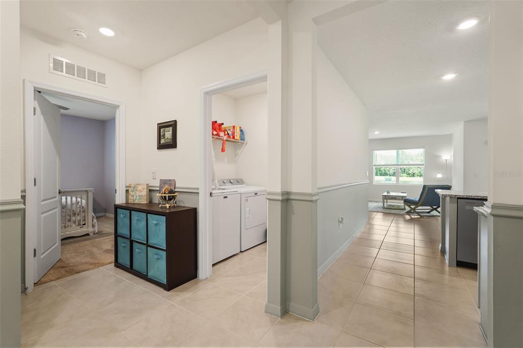 A hallway with tile flooring leads to a laundry room, a bedroom, and a living area — 3683 BOTANICAL WAY, SANFORD, FL