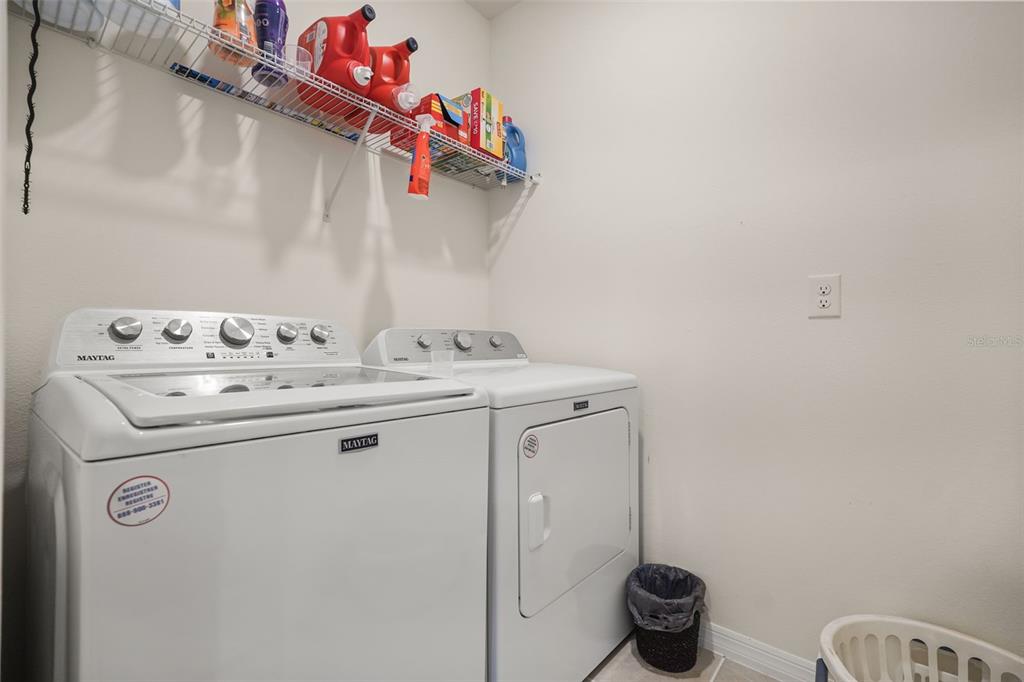 A laundry room features a white Maytag washer and dryer with wire shelving above — 3683 BOTANICAL WAY, SANFORD, FL