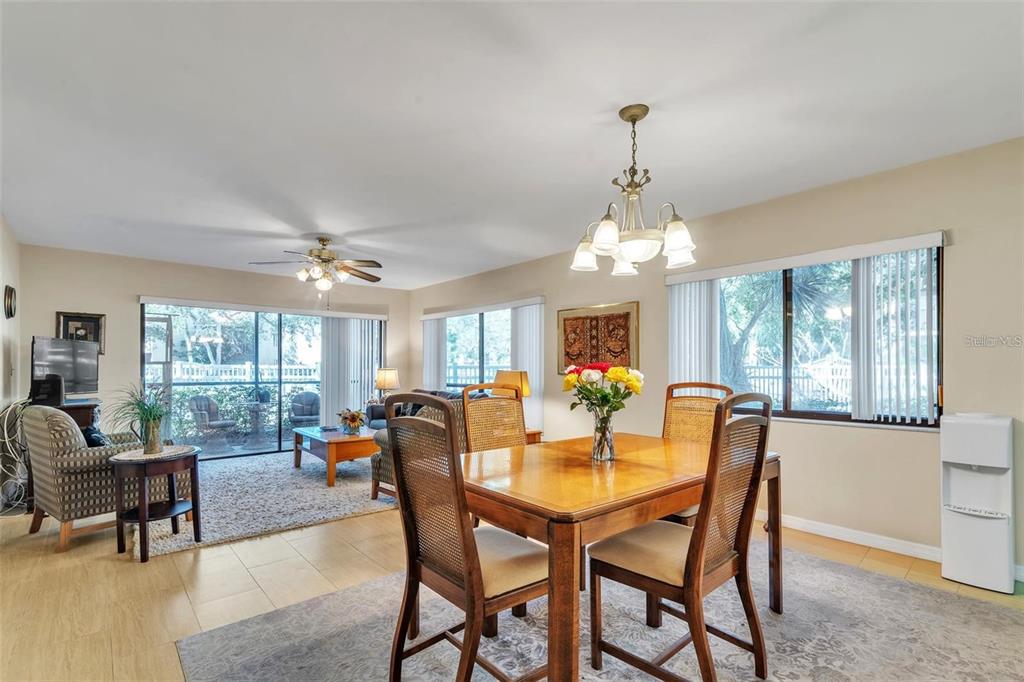 A dining area with a wooden table and chairs sits adjacent to a living room — 700 STARKEY ROAD UNIT 1114, LARGO, FL