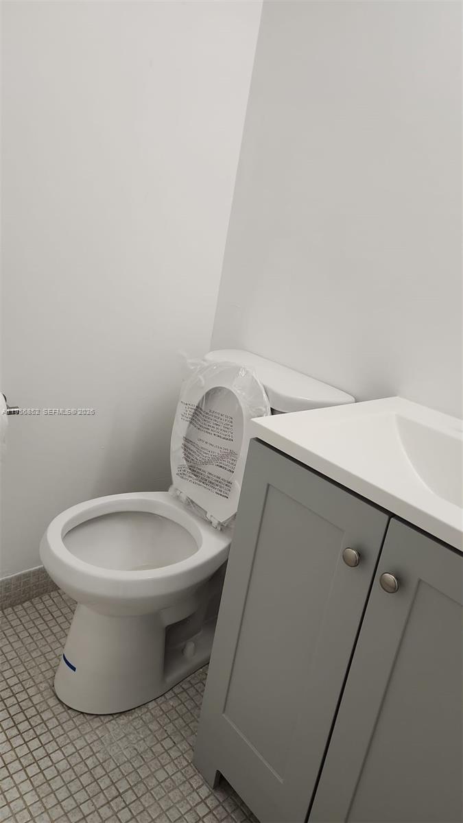 A bathroom features a white toilet with a plastic-covered seat next to a gray vanity — 4174 Inverrary Dr # 311, Lauderhill FL 33319, LAUDERHILL, FL