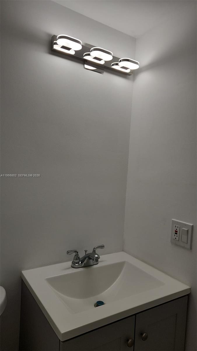 A bathroom features a white vanity, a chrome faucet, and a three-light wall fixture — 4174 Inverrary Dr # 311, Lauderhill FL 33319, LAUDERHILL, FL