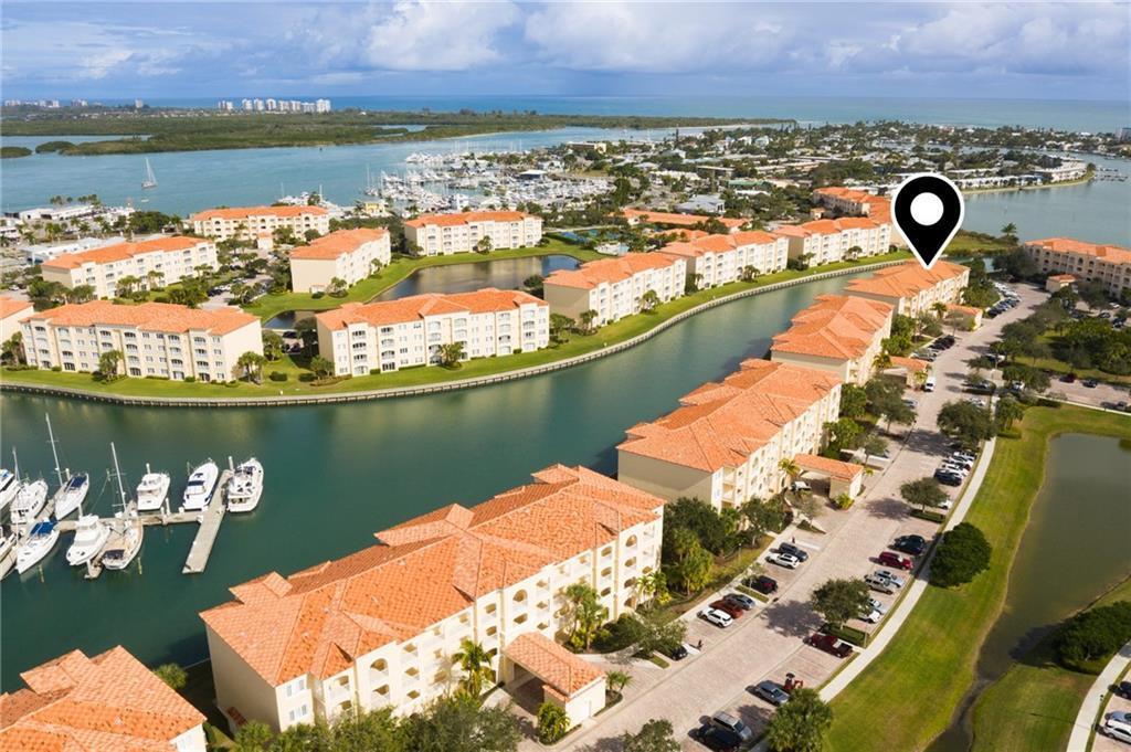 An aerial view shows multi-story residential buildings with orange tile roofs surrounding a canal — HUTCHINSON ISLAND, FL