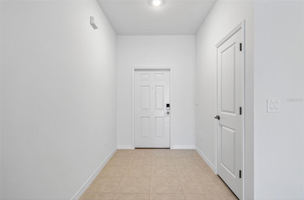 A bright entryway features white walls, tile flooring, a front door, and a side door — 11075 65TH TERRACE E, PALMETTO, FL