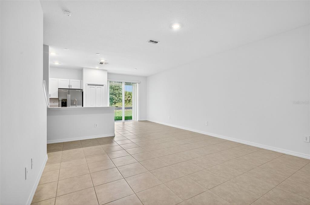 An open-concept living area features light tile flooring, white walls, and a kitchen with white cabinetry — 11075 65TH TERRACE E, PALMETTO, FL