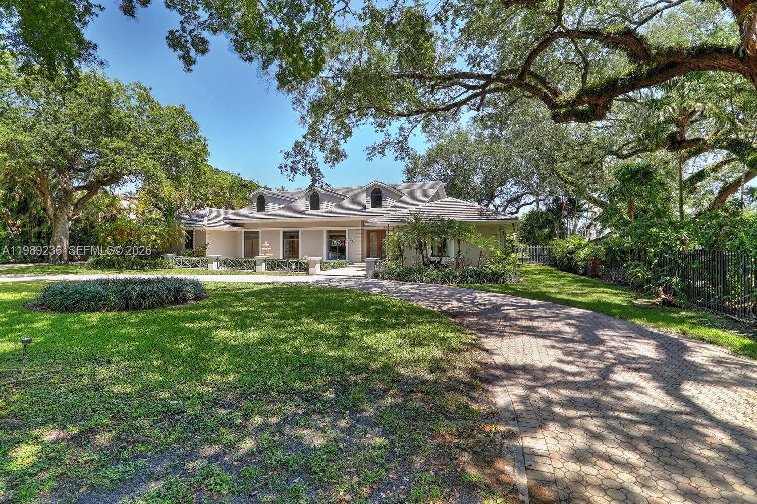 A single-story house with a paved driveway, dormer windows, and large oak trees — 3425 Alhambra Cir, Coral Gables FL 33134, CORAL GABLES, FL