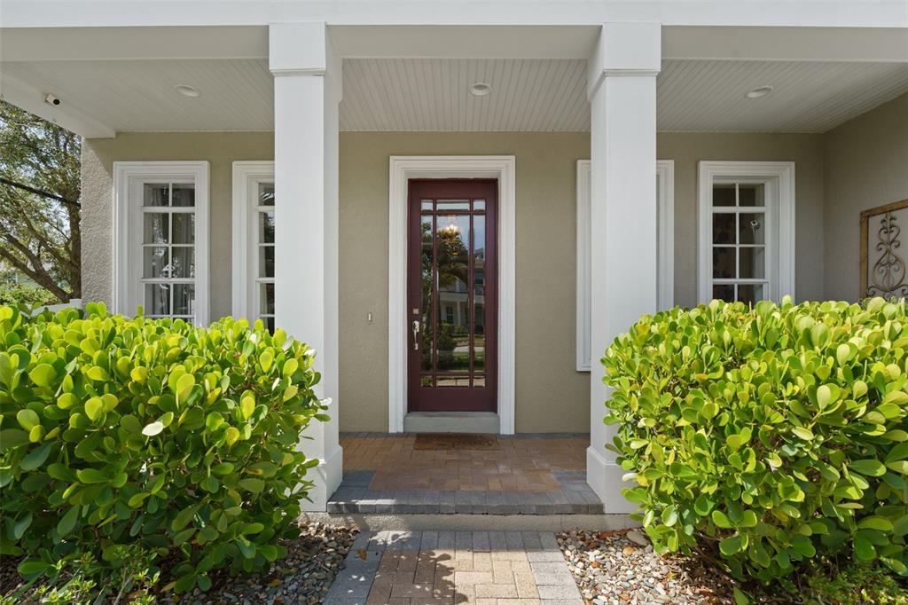 A front porch with a dark red glass-paneled door, white columns, and two large bushes — 3317 W LEONA STREET, TAMPA, FL