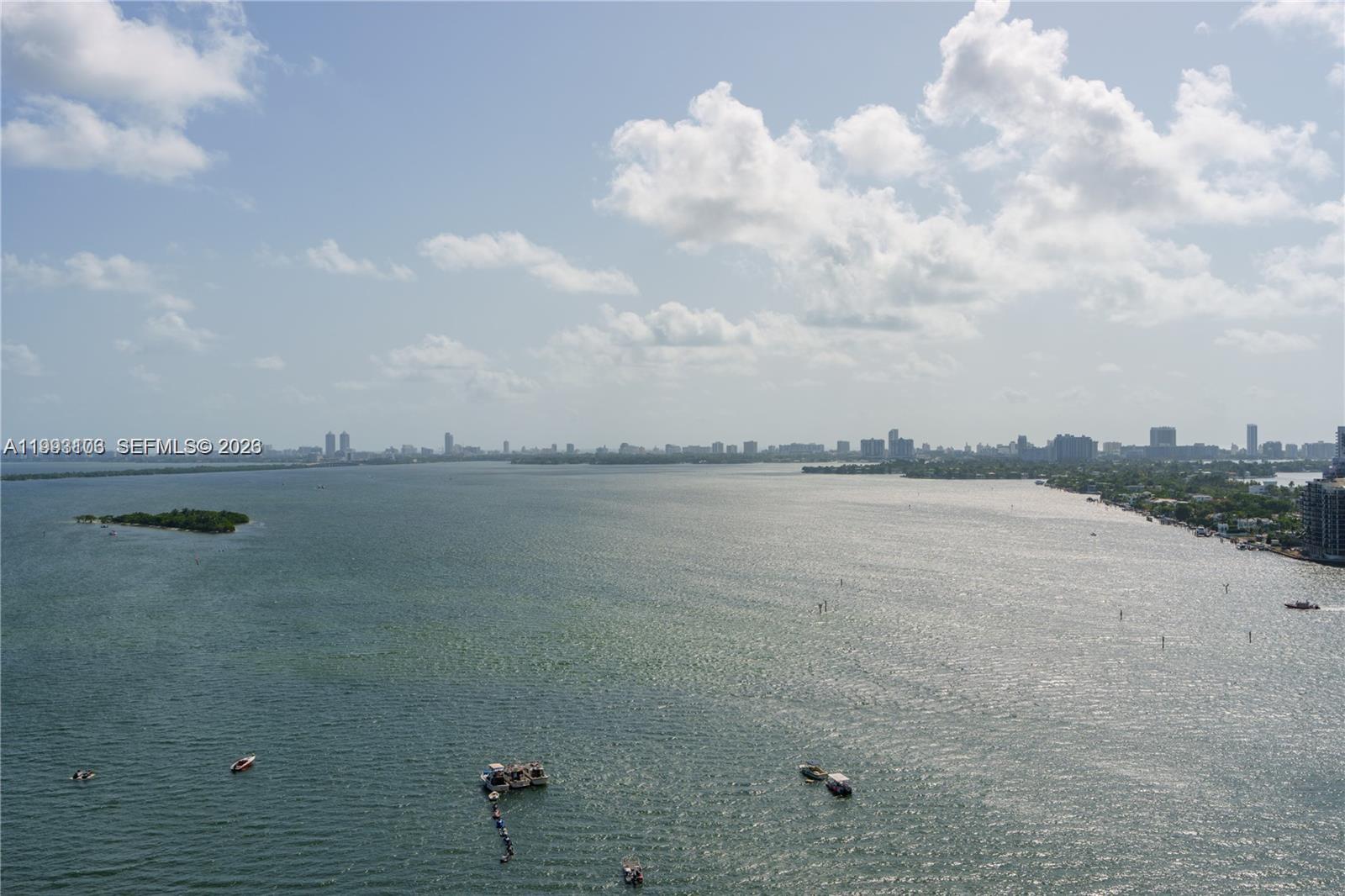 An aerial view shows a large body of water with several boats and a distant city skyline — 1750 N Bayshore Dr # 2401, Miami FL 33132, MIAMI, FL